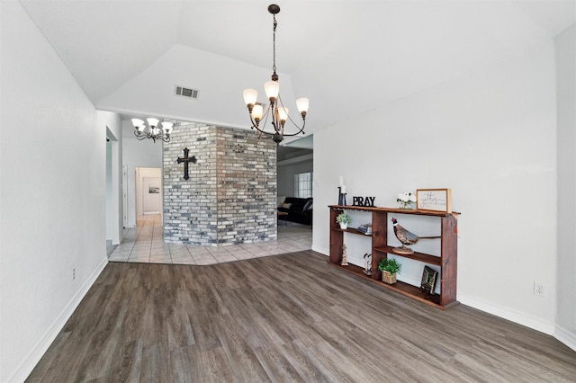 unfurnished dining area with visible vents, lofted ceiling, wood finished floors, and a notable chandelier