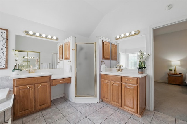 bathroom featuring vaulted ceiling, a stall shower, two vanities, a sink, and tile patterned floors