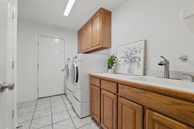 laundry area with a sink, cabinet space, light tile patterned floors, and washing machine and clothes dryer
