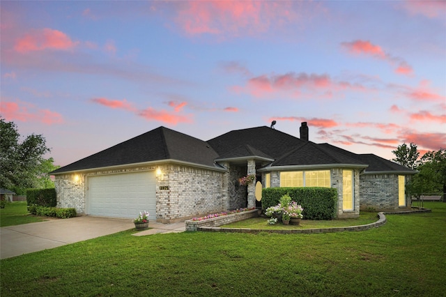 single story home featuring a chimney, a yard, brick siding, concrete driveway, and an attached garage