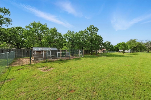 view of yard featuring fence, exterior structure, and an outbuilding