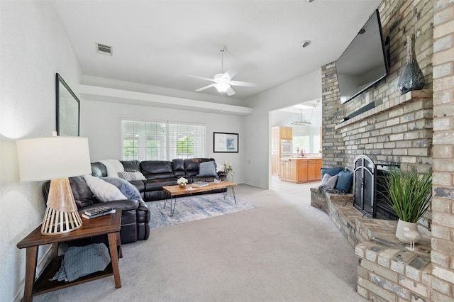 living area with a ceiling fan, visible vents, light carpet, and a fireplace
