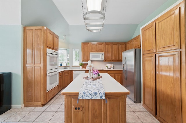 kitchen with a sink, light tile patterned floors, light countertops, lofted ceiling, and white appliances
