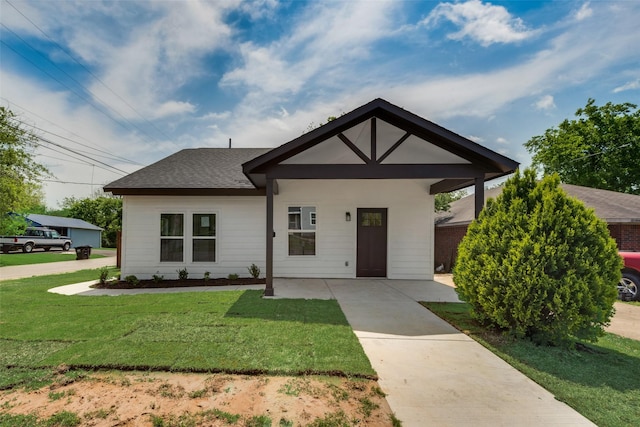 view of front of house featuring a front yard, driveway, and a shingled roof