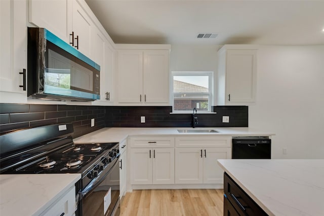 kitchen featuring white cabinets, visible vents, black appliances, a sink, and light wood finished floors