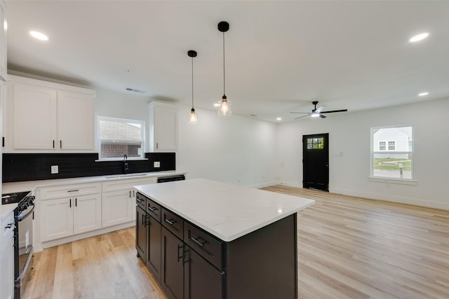 kitchen featuring a sink, black range with gas cooktop, decorative backsplash, and white cabinets