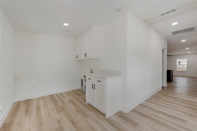 laundry area with light wood-style floors, visible vents, and baseboards