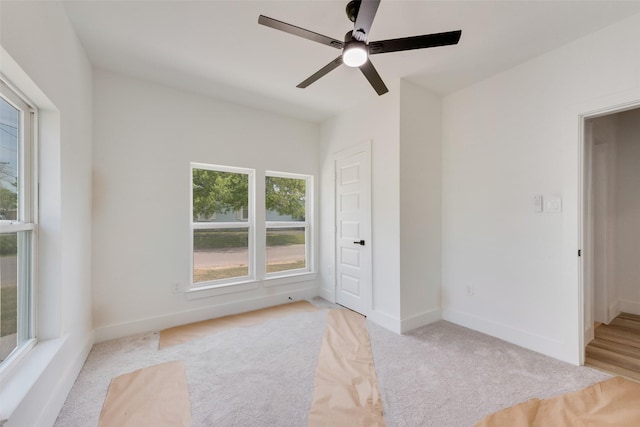 spare room with light carpet, baseboards, and a ceiling fan