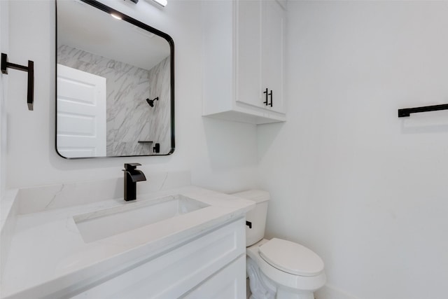 bathroom featuring toilet, vanity, and a shower
