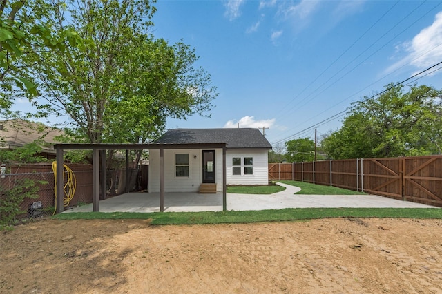 rear view of house featuring a patio area, entry steps, a fenced backyard, and a shingled roof
