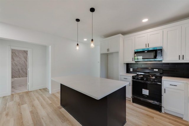 kitchen featuring stainless steel microwave, white cabinetry, and black gas range oven