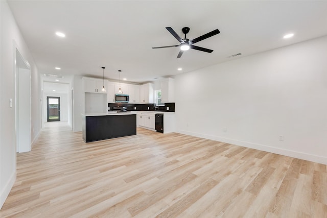 kitchen featuring stainless steel microwave, open floor plan, visible vents, and white cabinetry