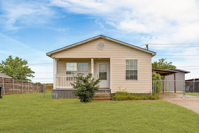 bungalow featuring fence, concrete driveway, covered porch, a carport, and a front yard