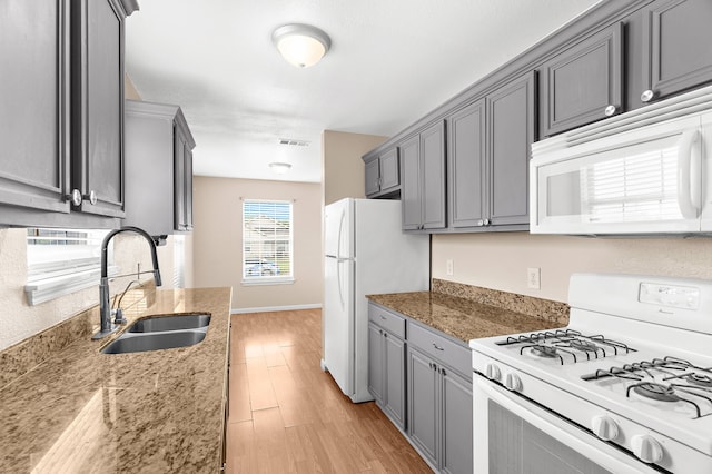kitchen featuring gray cabinetry, visible vents, a sink, and white appliances
