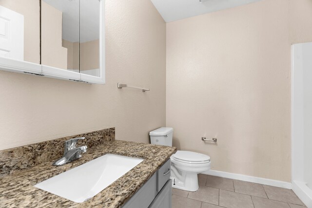 bathroom with baseboards, tile patterned flooring, vanity, and toilet