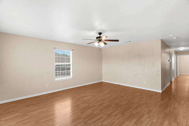 empty room with light wood-style floors, visible vents, a ceiling fan, and baseboards