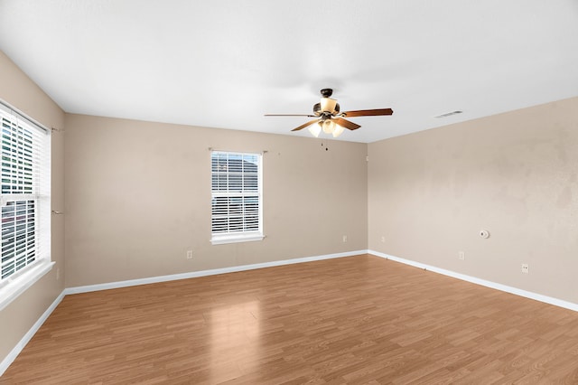 unfurnished room with baseboards, a ceiling fan, light wood-style floors, and visible vents