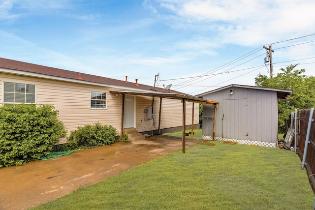 back of house featuring fence, an outdoor structure, entry steps, and a yard