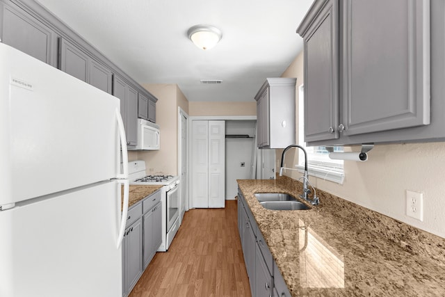 kitchen featuring light wood-style flooring, a sink, visible vents, gray cabinetry, and white appliances
