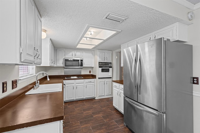 3206 Knights Haven Ln, Garland, TX 75044 - kitchen featuring appliances with stainless steel finishes, a sink, a textured ceiling, and white cabinets