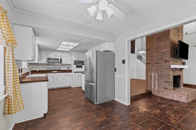 3206 Knights Haven Ln, Garland, TX 75044 - kitchen with appliances with stainless steel finishes, a sink, a textured ceiling, ceiling fan, and white cabinets