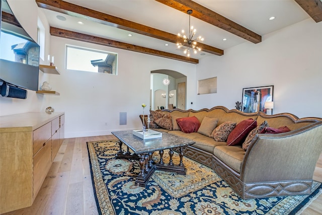 living room featuring recessed lighting, arched walkways, a chandelier, beamed ceiling, and light wood finished floors