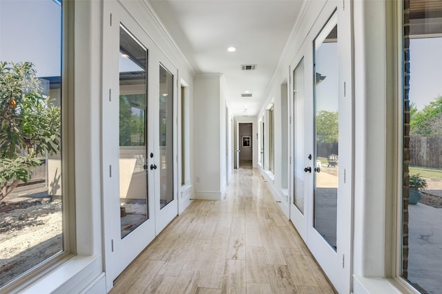 hall with french doors, light wood-type flooring, crown molding, and visible vents