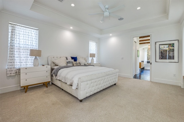 bedroom featuring light colored carpet, crown molding, and a tray ceiling