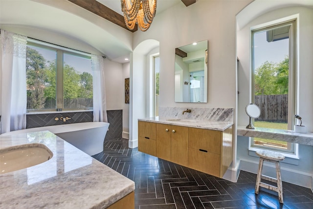 full bath featuring two vanities, a sink, an inviting chandelier, and baseboards