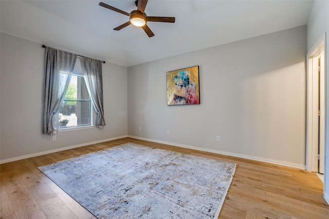 spare room with ceiling fan, baseboards, lofted ceiling, and light wood-type flooring