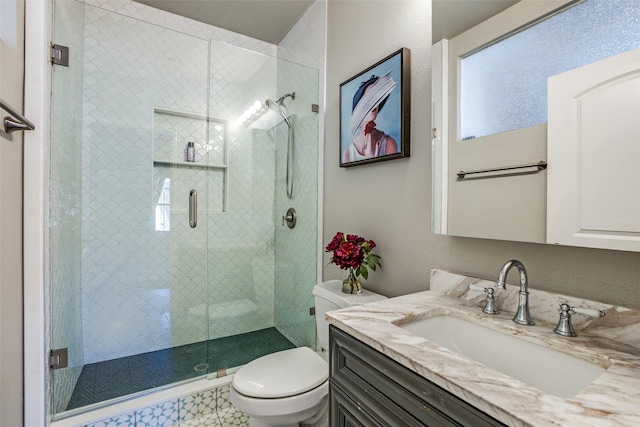 bathroom with a stall shower, toilet, and vanity
