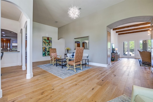 interior space featuring beam ceiling, hardwood / wood-style floors, baseboards, and arched walkways