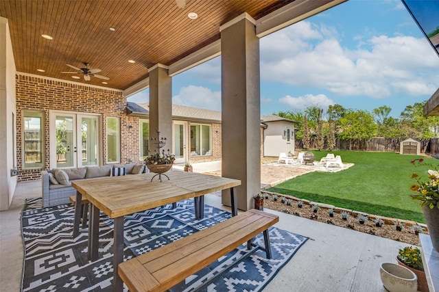 view of patio featuring an outdoor structure, ceiling fan, a fenced backyard, a storage shed, and french doors
