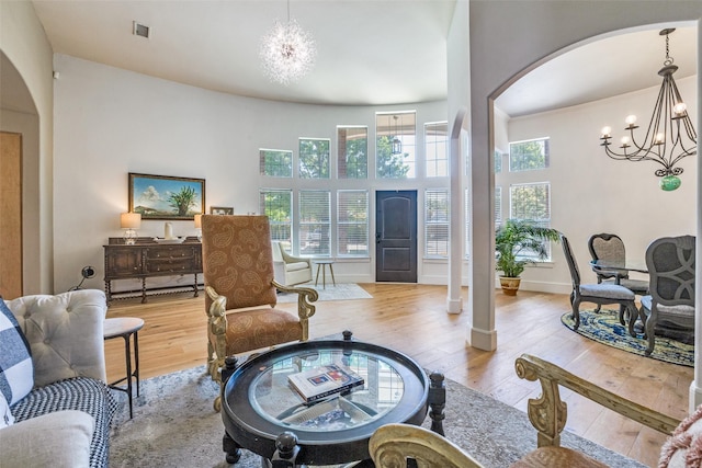 living room with an inviting chandelier, visible vents, wood-type flooring, and arched walkways