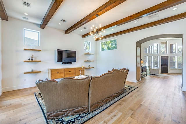 living room featuring baseboards, arched walkways, light wood finished floors, beam ceiling, and visible vents