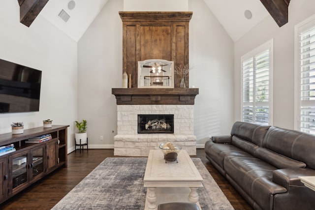 living room featuring high vaulted ceiling, dark wood finished floors, a stone fireplace, and visible vents