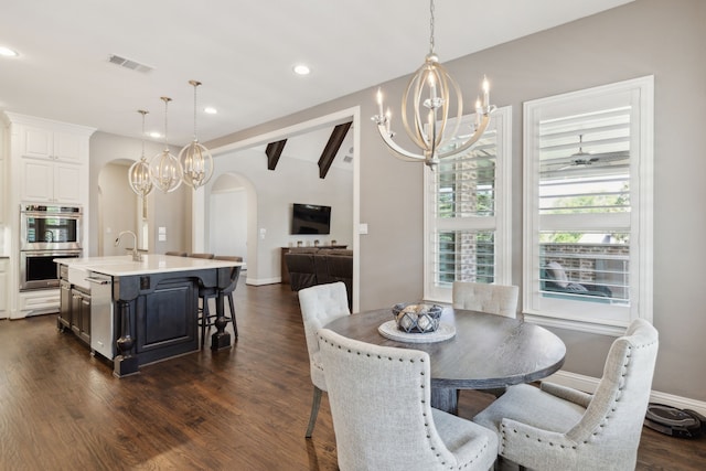 dining space featuring recessed lighting, arched walkways, dark wood-style floors, and an inviting chandelier