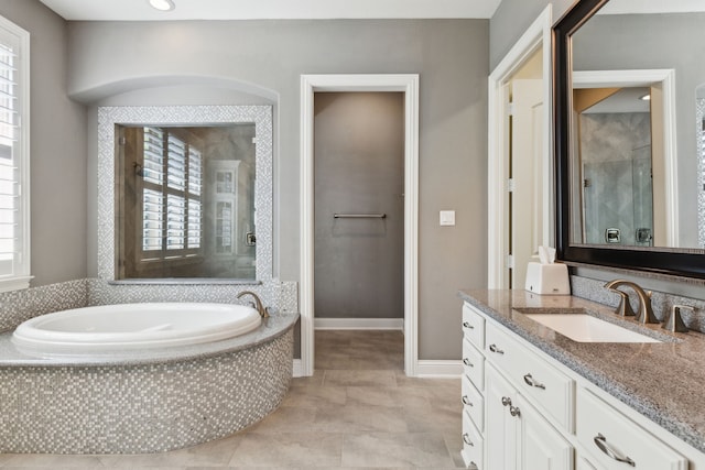 bathroom featuring tile patterned flooring, vanity, baseboards, a garden tub, and a shower