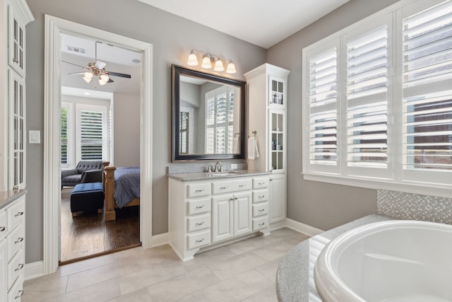 bathroom with baseboards, visible vents, a ceiling fan, a garden tub, and vanity