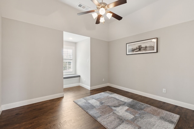 spare room featuring baseboards, visible vents, ceiling fan, and dark wood-style flooring