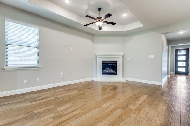 1624 Sweetwater Way, Celina, TX 75009 - unfurnished living room featuring a raised ceiling, light wood-style floors, a ceiling fan, a glass covered fireplace, and recessed lighting