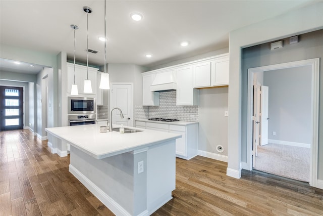 1624 Sweetwater Way, Celina, TX 75009 - kitchen featuring appliances with stainless steel finishes, a kitchen island with sink, custom range hood, tasteful backsplash, and white cabinetry
