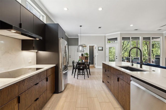 kitchen featuring ornamental molding, light countertops, appliances with stainless steel finishes, a sink, and hanging light fixtures