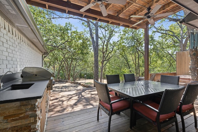 wooden deck with ceiling fan, exterior kitchen, and outdoor dining space