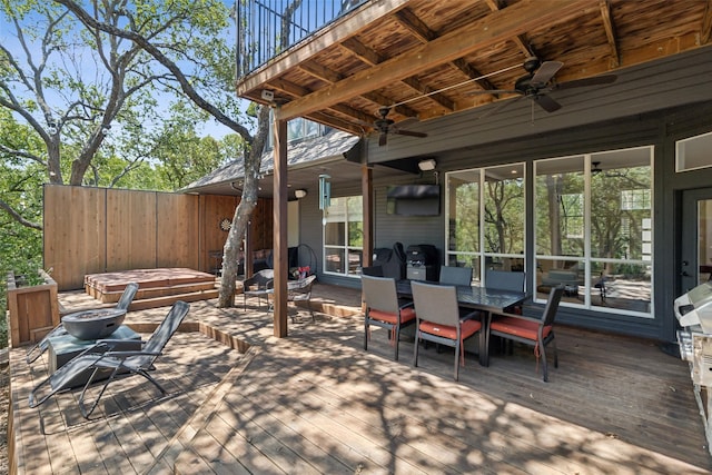 view of patio / terrace featuring outdoor dining area, ceiling fan, a hot tub, an outdoor fire pit, and a deck