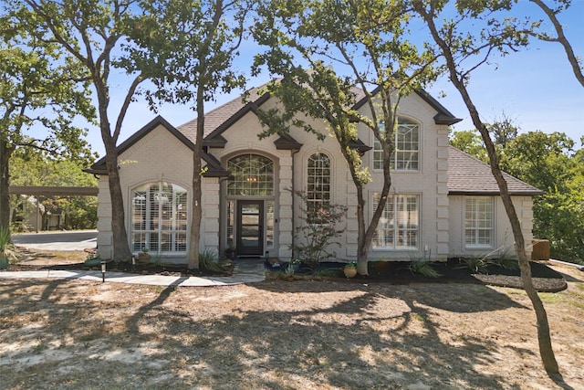 view of front of property with brick siding and a shingled roof