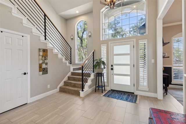 entrance foyer with baseboards, stairway, a chandelier, and a towering ceiling