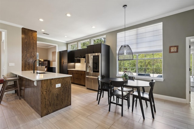 kitchen with modern cabinets, ornamental molding, light countertops, and stainless steel fridge