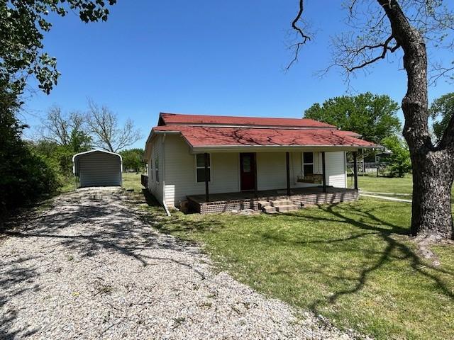 view of front facade featuring a detached carport, a front lawn, and driveway