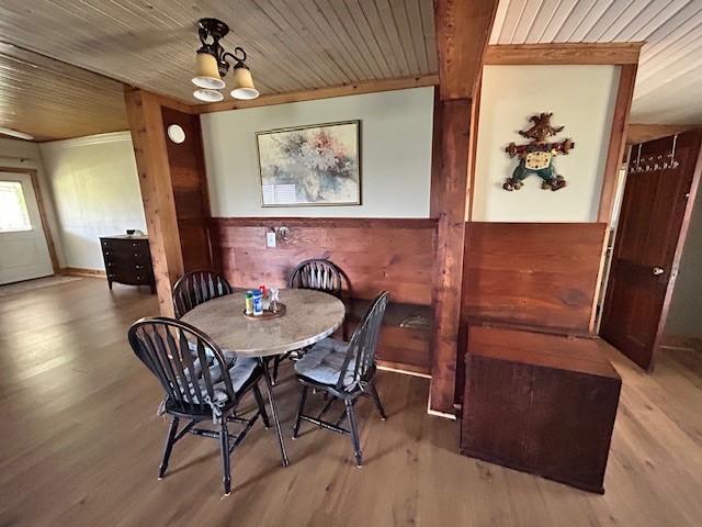 dining room featuring wood finished floors, wood walls, a notable chandelier, and wooden ceiling